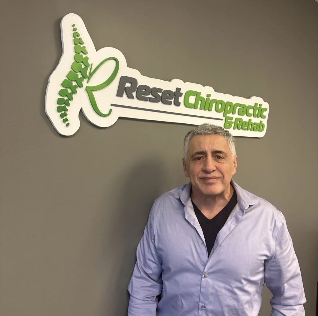 A naturopath near me standing in front of a sign that says rest chiropractic.
