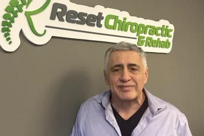 A man standing in front of a sign that says rest chiropractic.